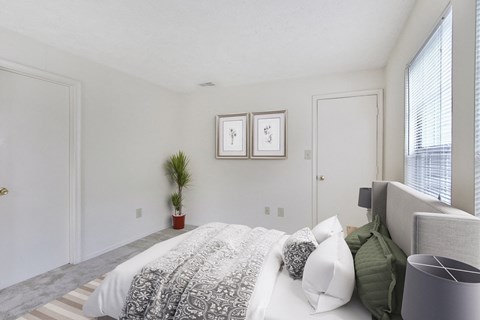 a bedroom with a bed and a chair and a window