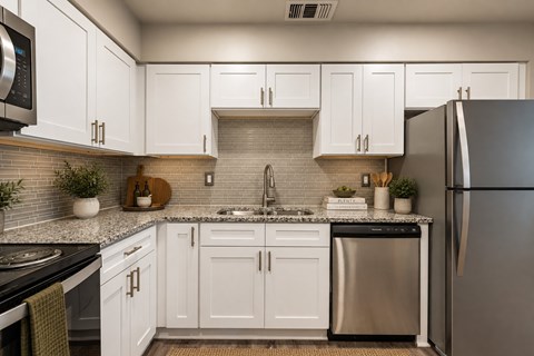 A kitchen with white cabinets and a black refrigerator.