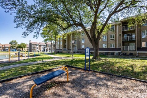 our apartments have a park with a bench and a tree