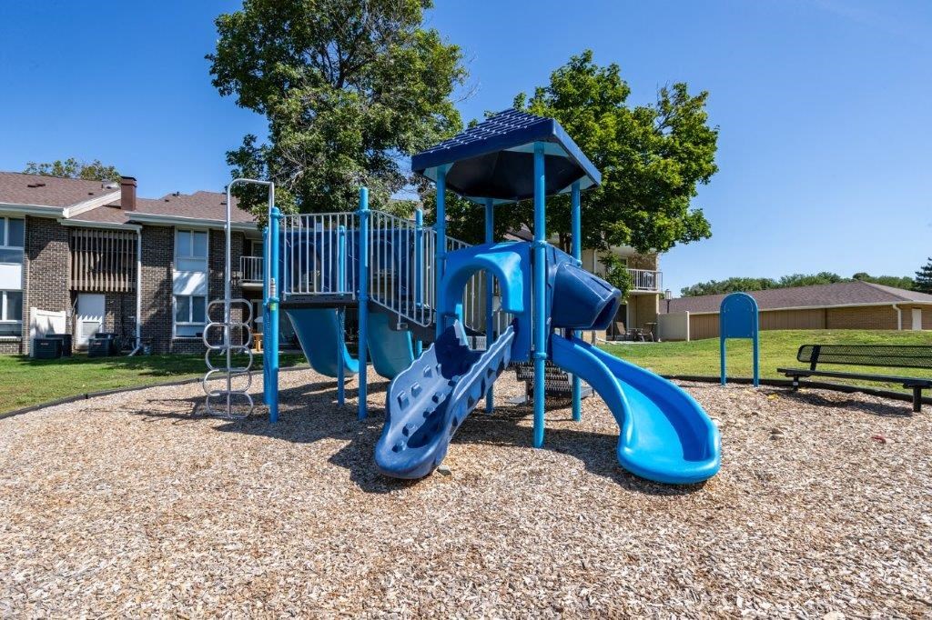 a playground with a blue playset and a swing set