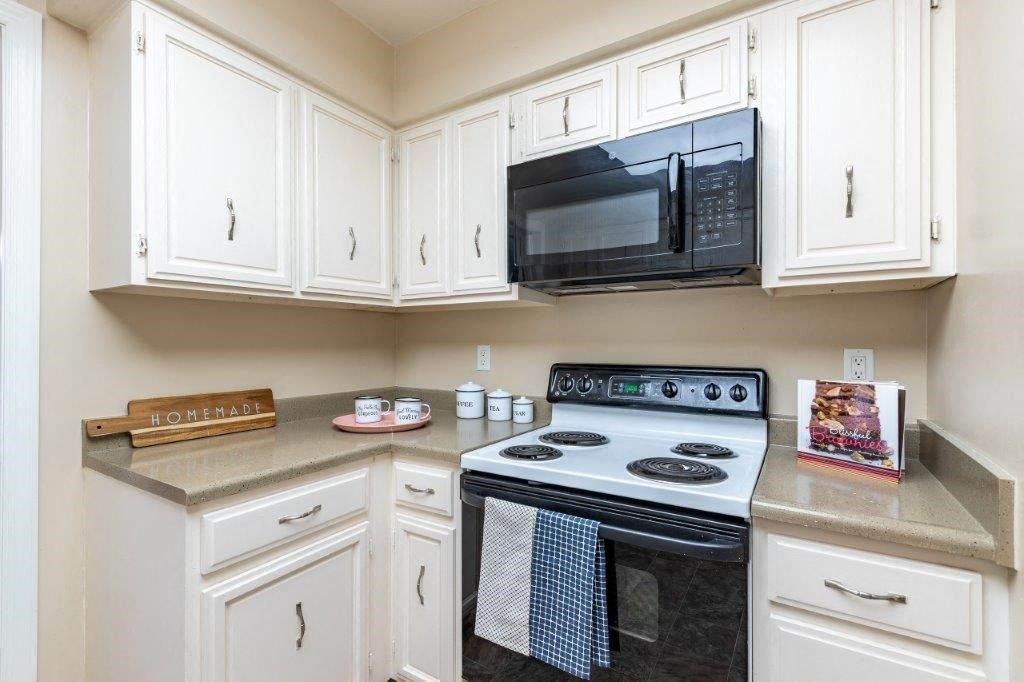 a kitchen with white cabinets and a stove and a microwave