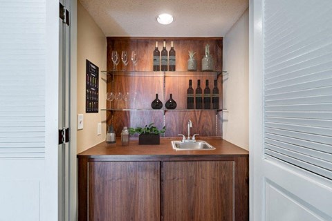 a kitchen with a sink and bottles on the wall