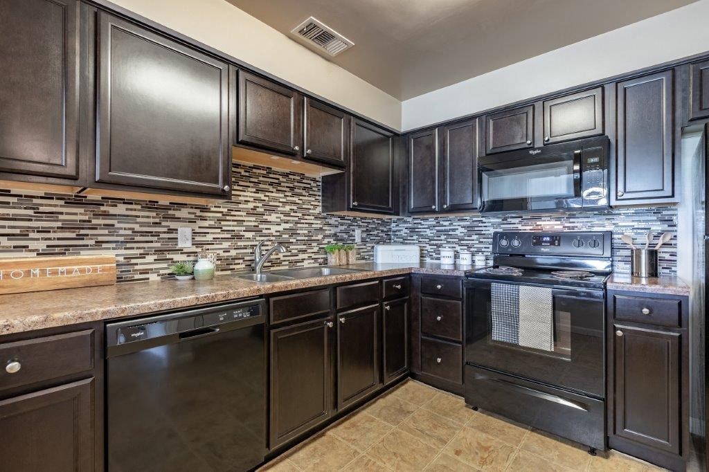 a kitchen with stainless steel appliances and black cabinets