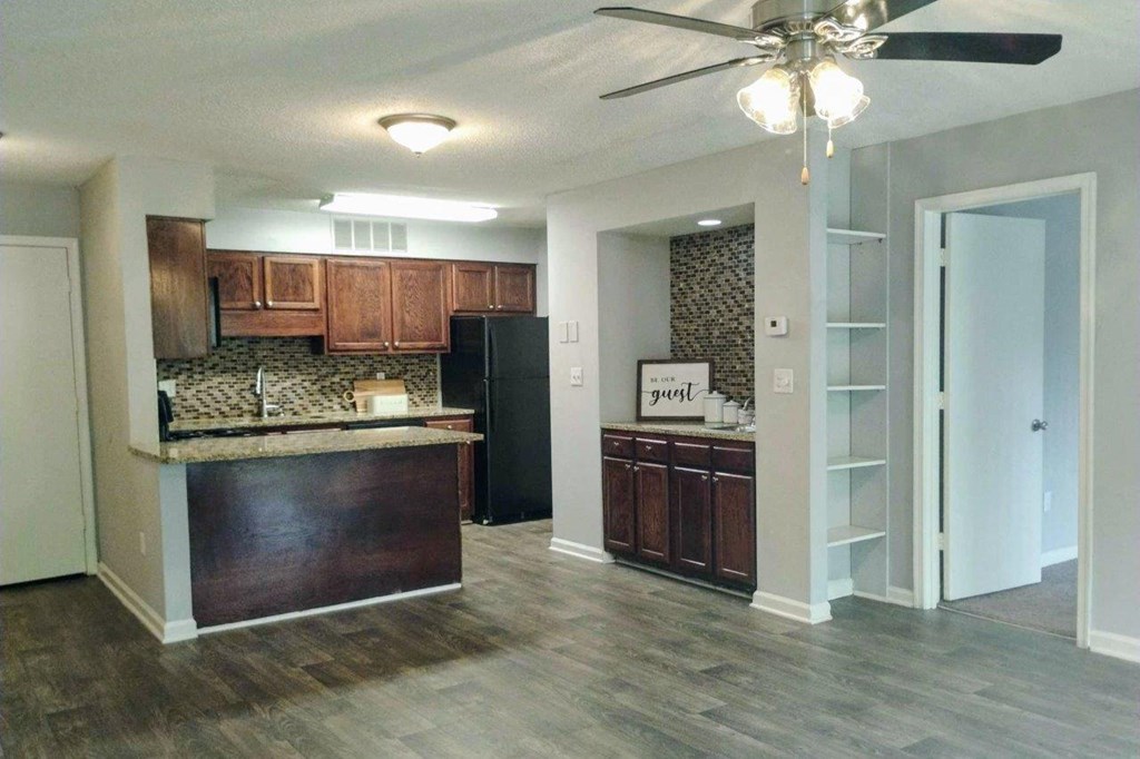 A kitchen with a black refrigerator and wooden cabinets.