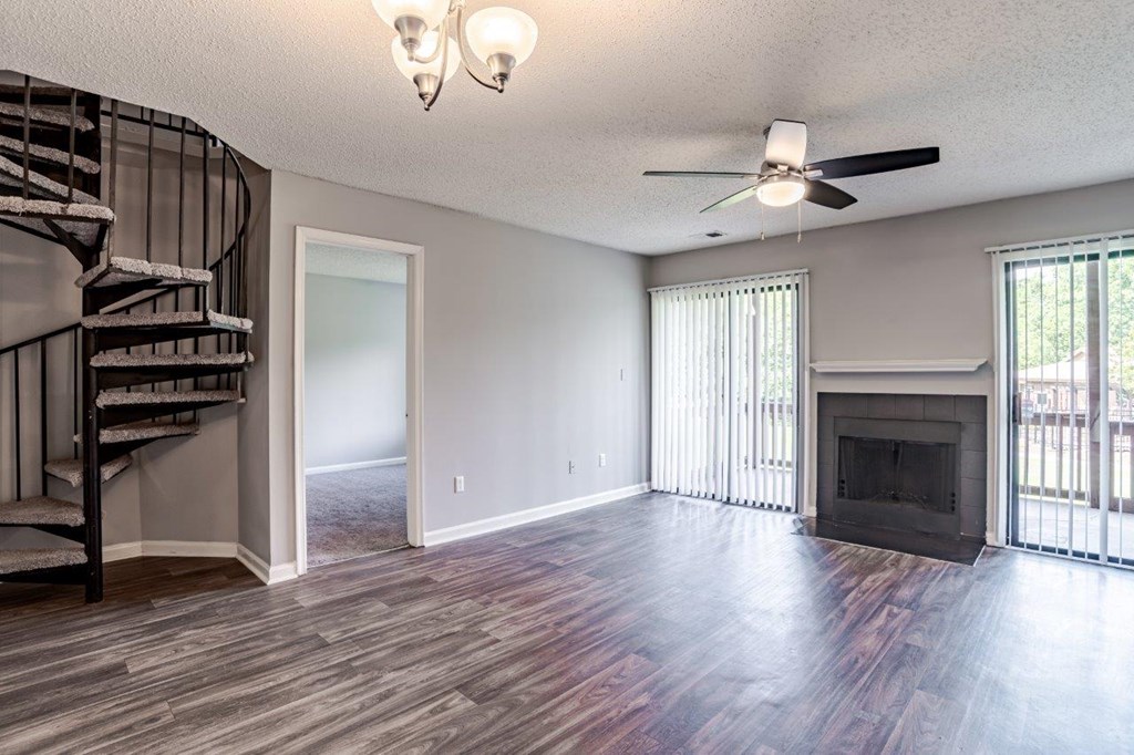 A spacious living room with a fireplace and a spiral staircase.