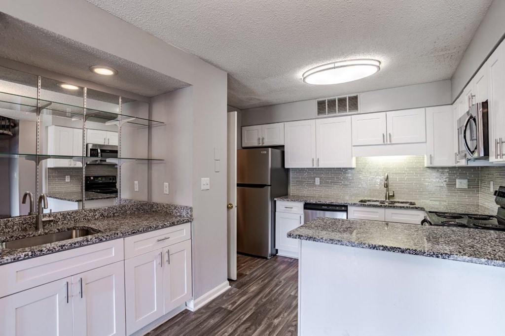 A kitchen with white cabinets and a granite countertop.