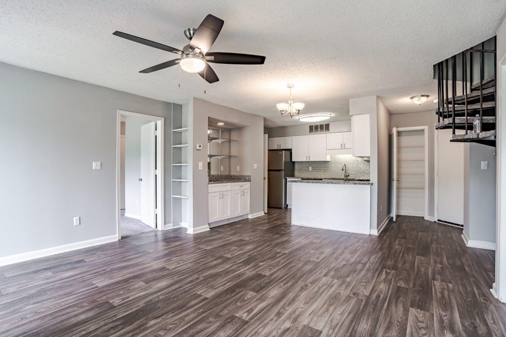 A room with a ceiling fan and wooden flooring.