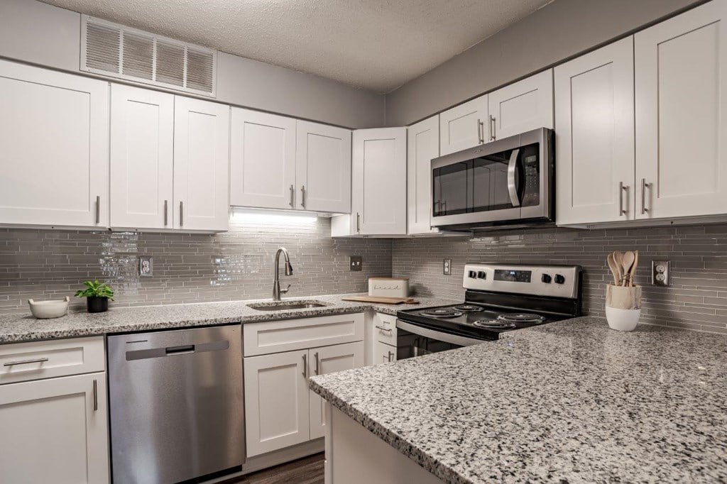 A kitchen with granite countertops and white cabinets.