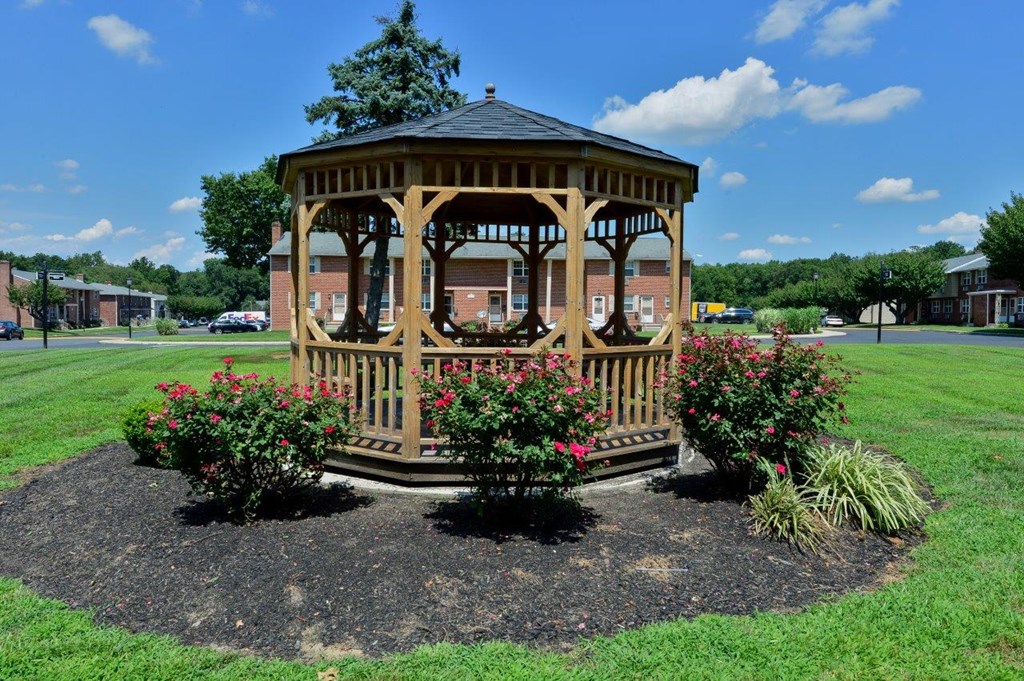 a gazebo with benches and flowers in a park