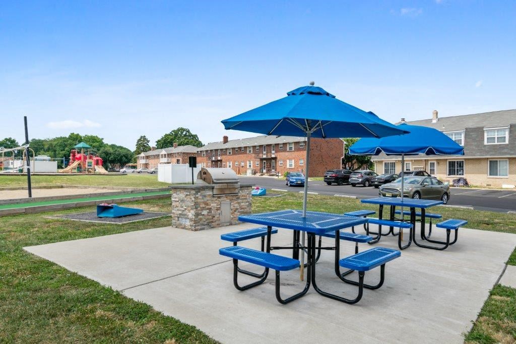 a picnic table with umbrellas and benches on a sidewalk