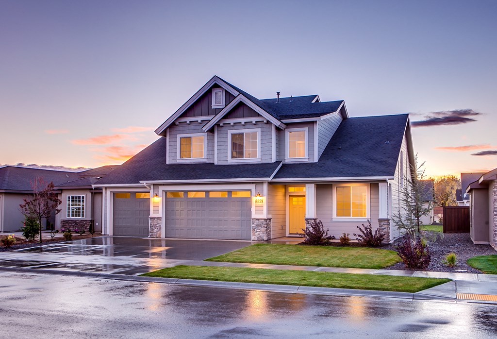 a house with lights on in the driveway at dusk