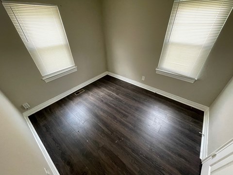 A room with wooden floors and two windows.