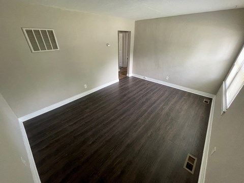 A room with wooden flooring and a door on the right side.