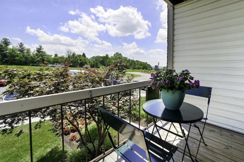 a balcony with a table and chairs and a view of a garden