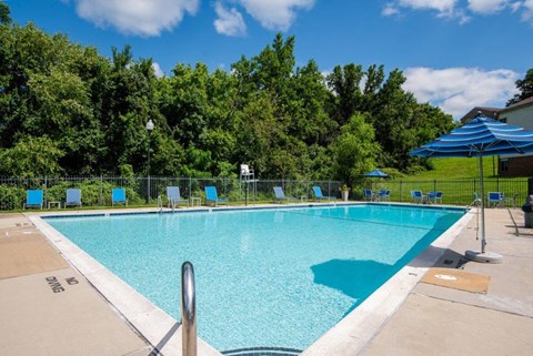 a swimming pool with blue chairs and an umbrella