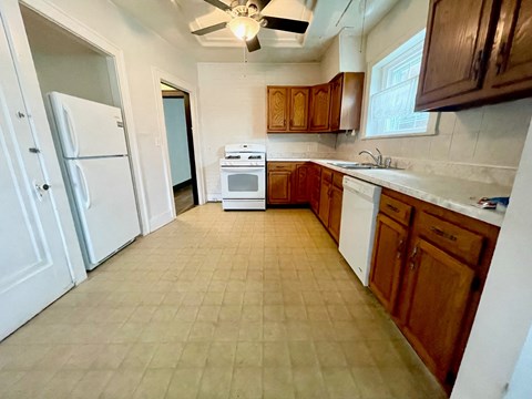 an empty kitchen with white appliances and wooden cabinets