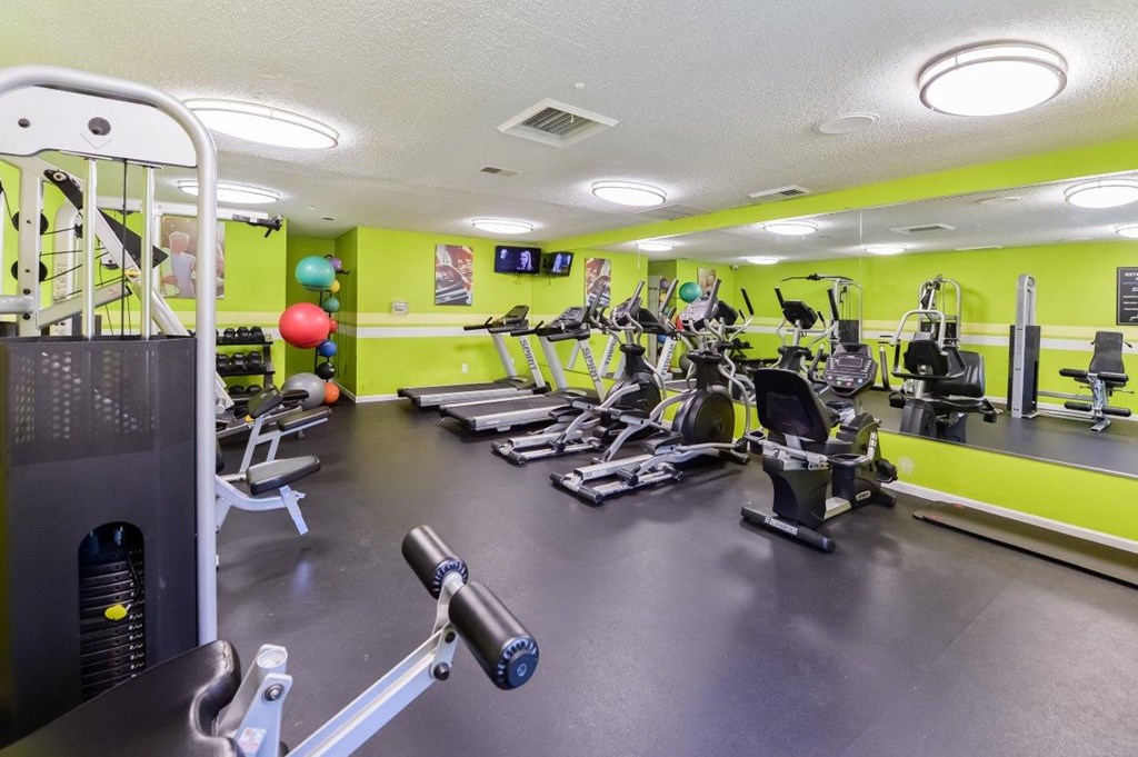 a gym with cardio equipment and weights on the floor
