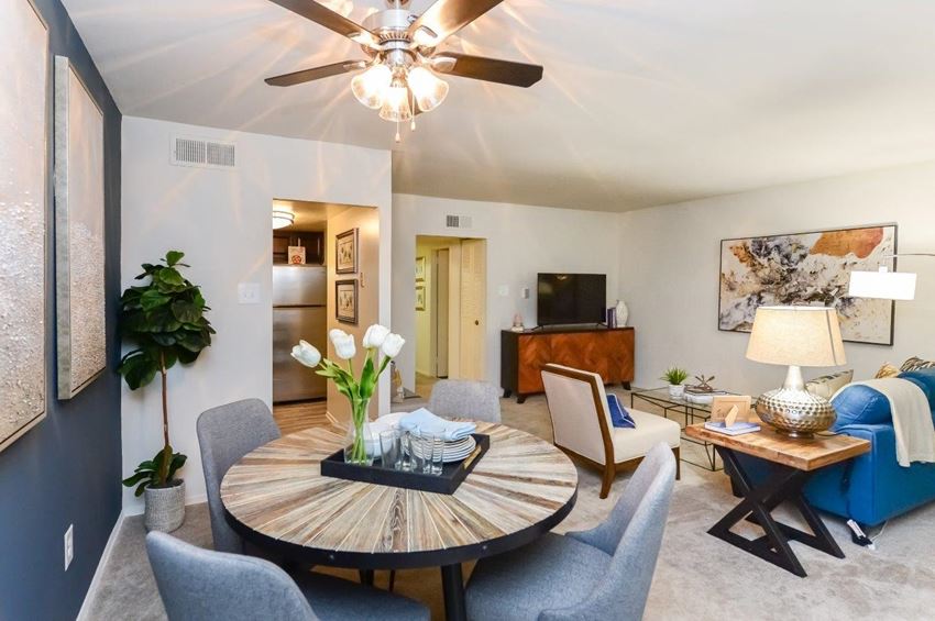 a living room with a table and a ceiling fan