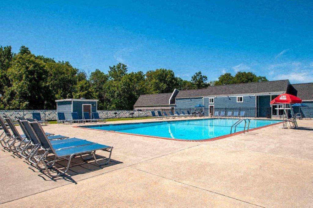 a swimming pool with chairs around it in front of a building