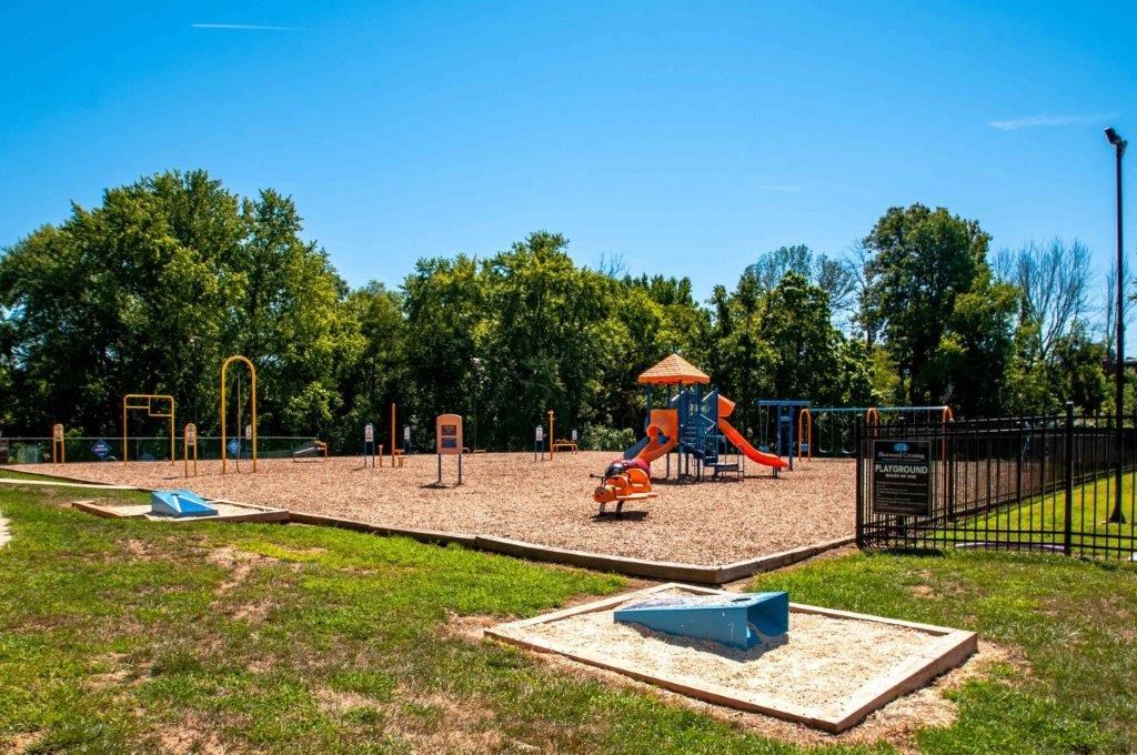 a playground with a swing set and a sandbox in a park