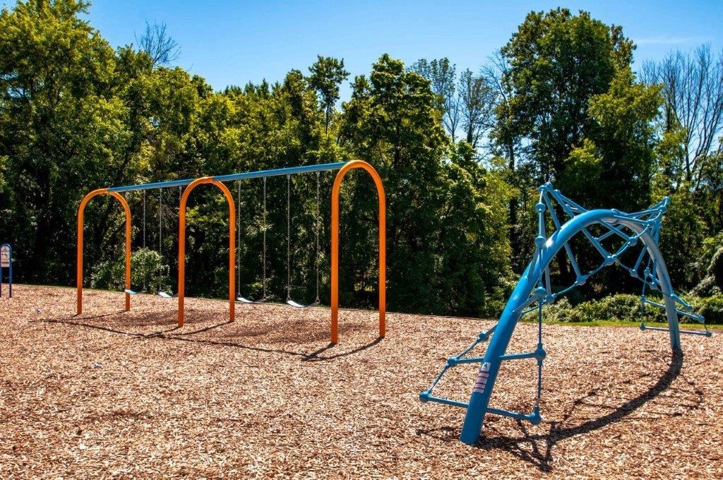 a swing set on a playground with trees in the background