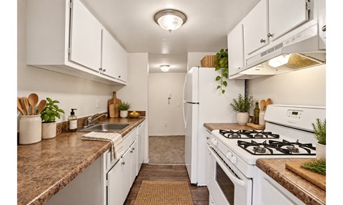 A kitchen with white cabinets and a brown countertop.
