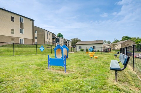 A playground with a blue slide and a bench in front of apartment buildings.