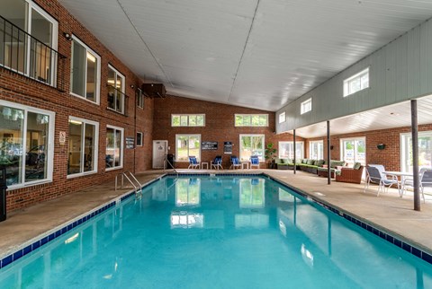 A large indoor swimming pool with a tiled edge and a brick wall.