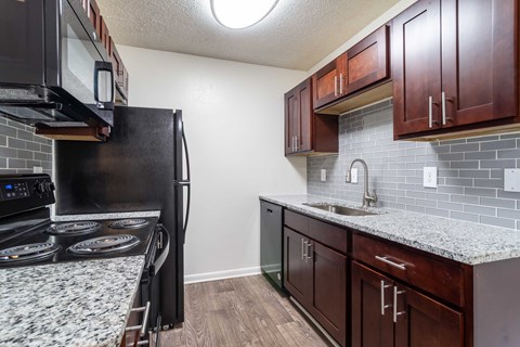 A kitchen with a black stove top oven and a black microwave above it.