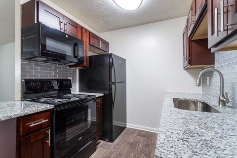 A kitchen with black appliances and wooden cabinets.