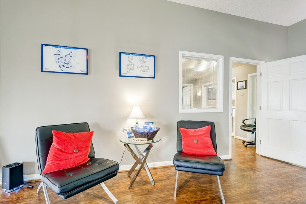 a living room with two chairs and a table with a red pillow