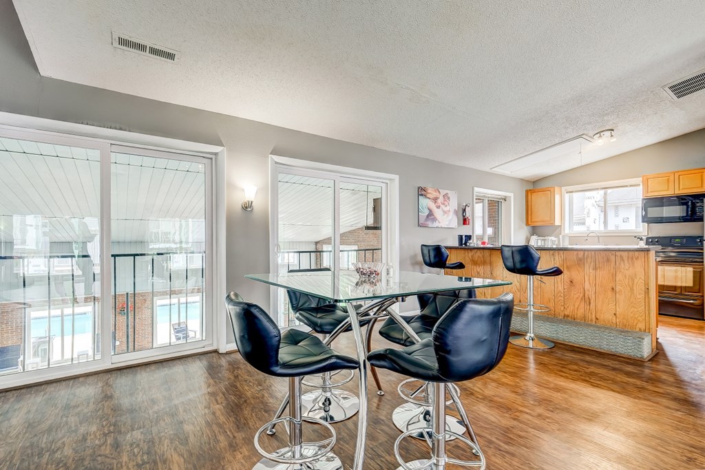 a dining room with a glass table and chairs     and a kitchen