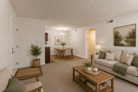 A living room with a couch, coffee table, and a dining table.