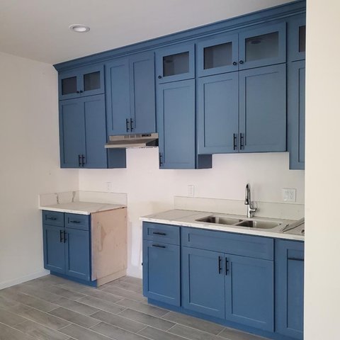 A kitchen with blue cabinets and a white counter top.
