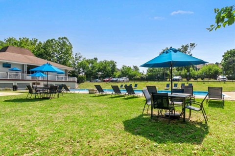 a large yard with tables and umbrellas and a pool