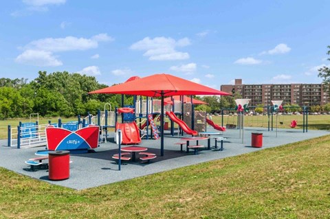 a playground with a red umbrella and benches