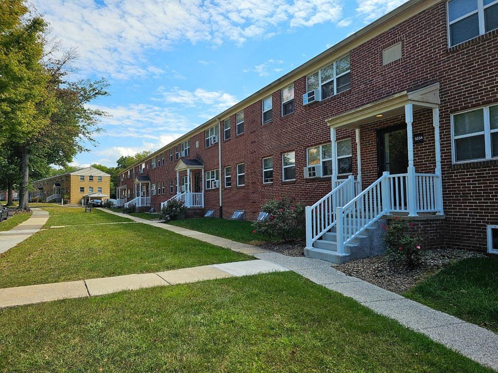 a sidewalk in front of a brick apartment building