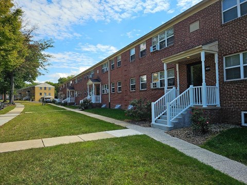 a sidewalk in front of a brick apartment building