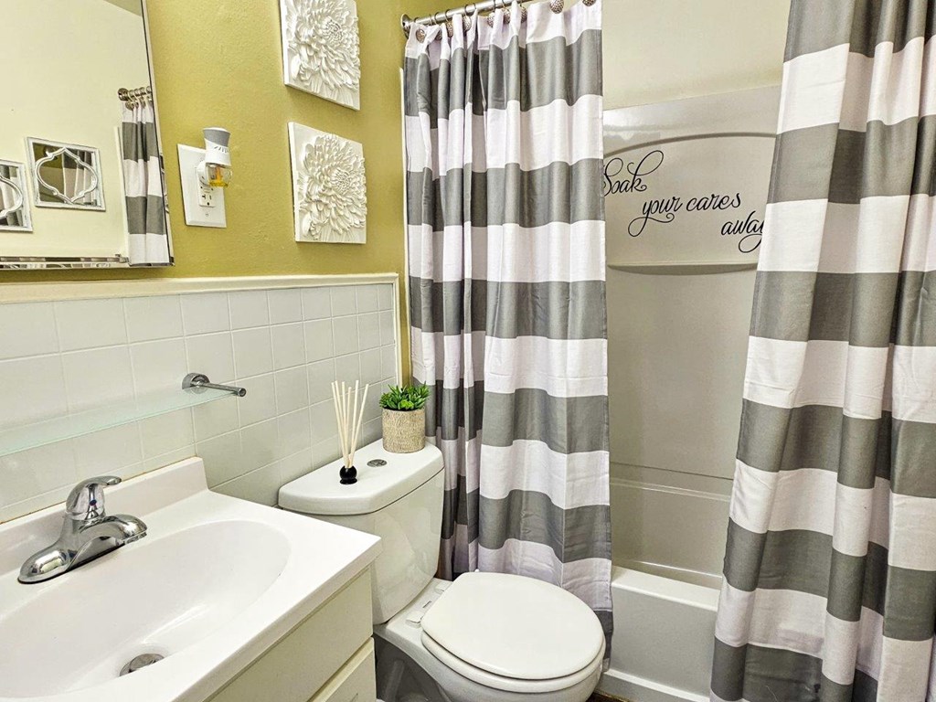 a bathroom with a shower curtain and a sink and a toilet