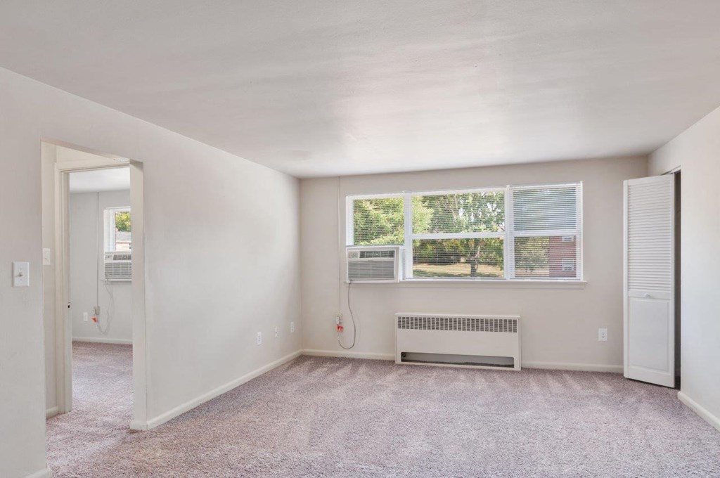 an empty living room with a window and a radiator
