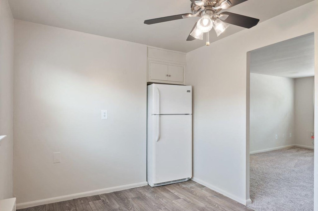 a white refrigerator in a white room with a ceiling fan