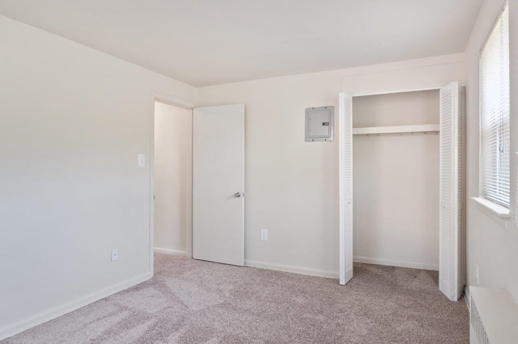 an empty bedroom with a closet and a window
