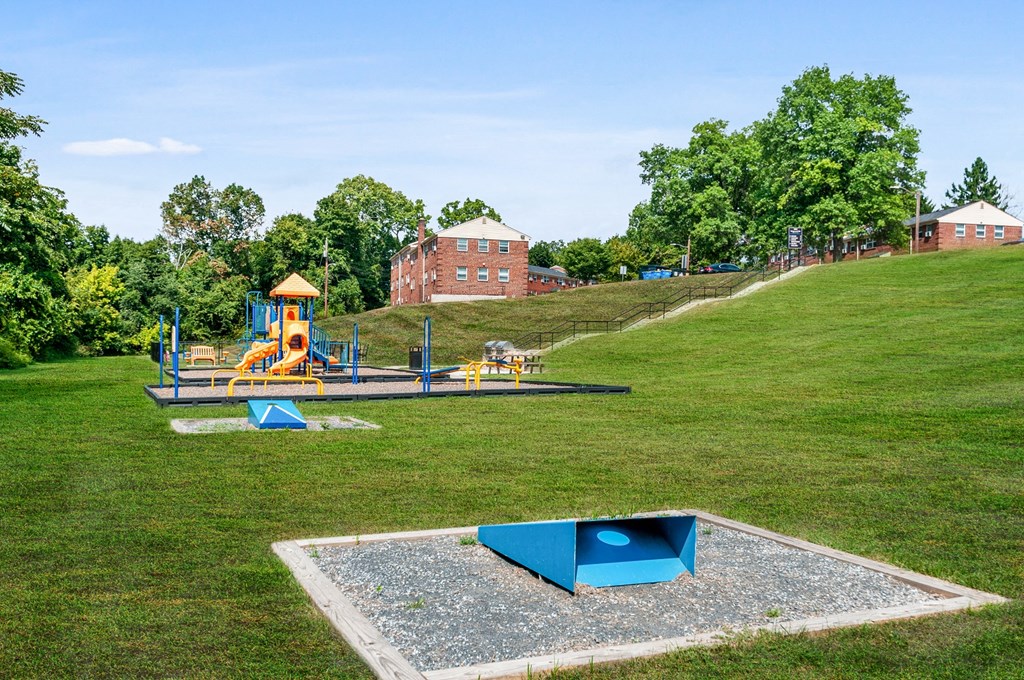 a park with a playground and a swing set on a hill