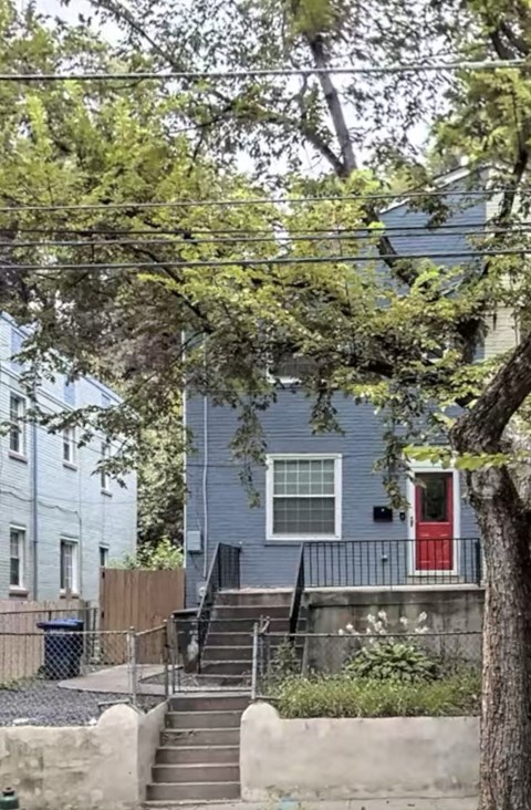 a blue house with a red door and a tree