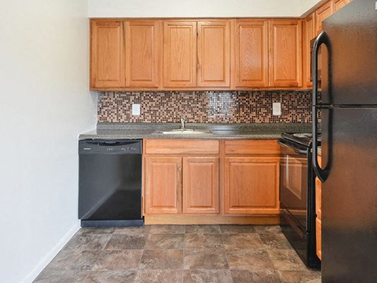 a kitchen with wooden cabinets and a black dishwasher