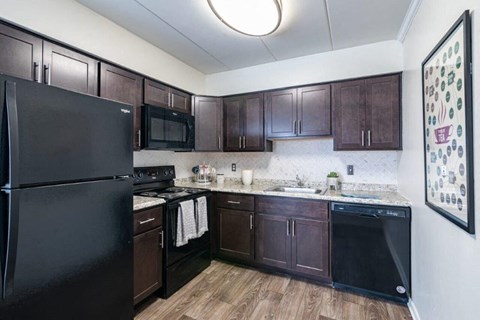 a kitchen with black appliances and dark wood cabinets