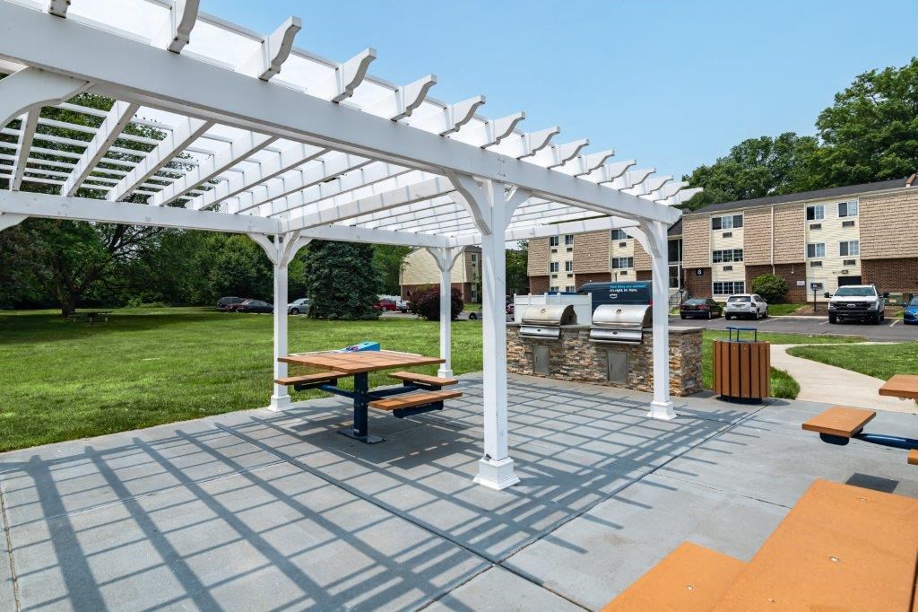 a patio with a picnic table and a white pergola