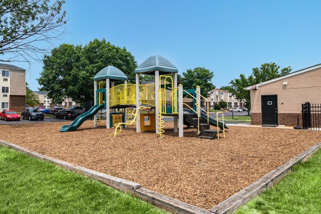a playground with a yellow swing set in a park