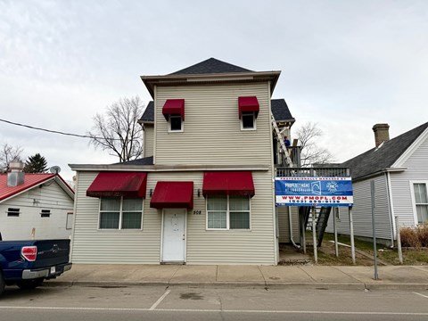 A building with a red awning and a blue sign in front of it.