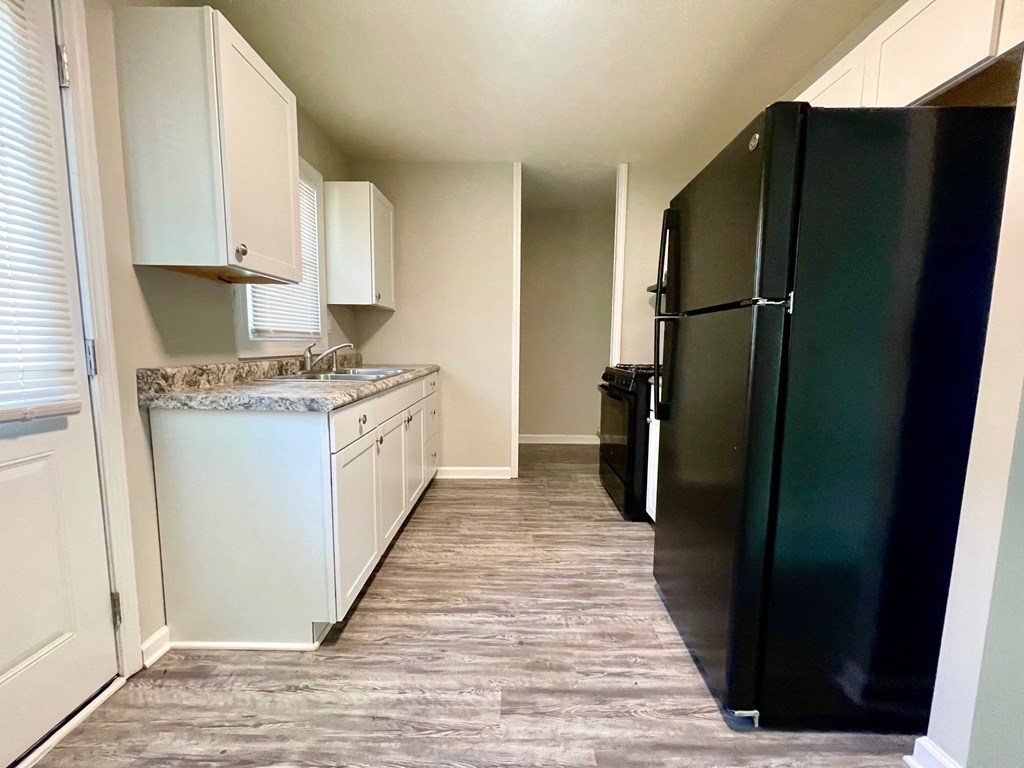 a kitchen with white cabinets and a black refrigerator